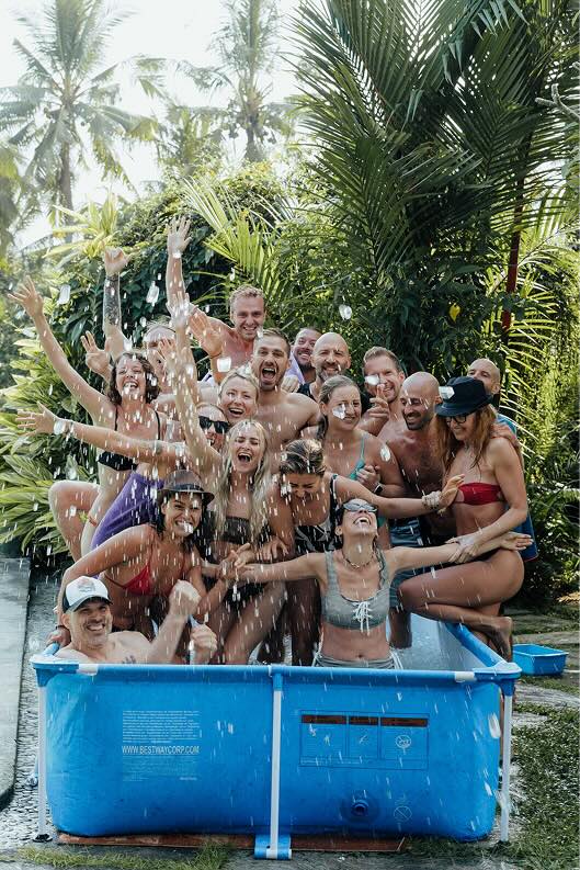 Breathwork facilitator training bali - participants a big group is raising their arms in a pool they are all in swimming clothes.