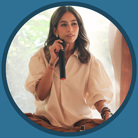 Sonakshi with microphone in hand explaining while seated on floor