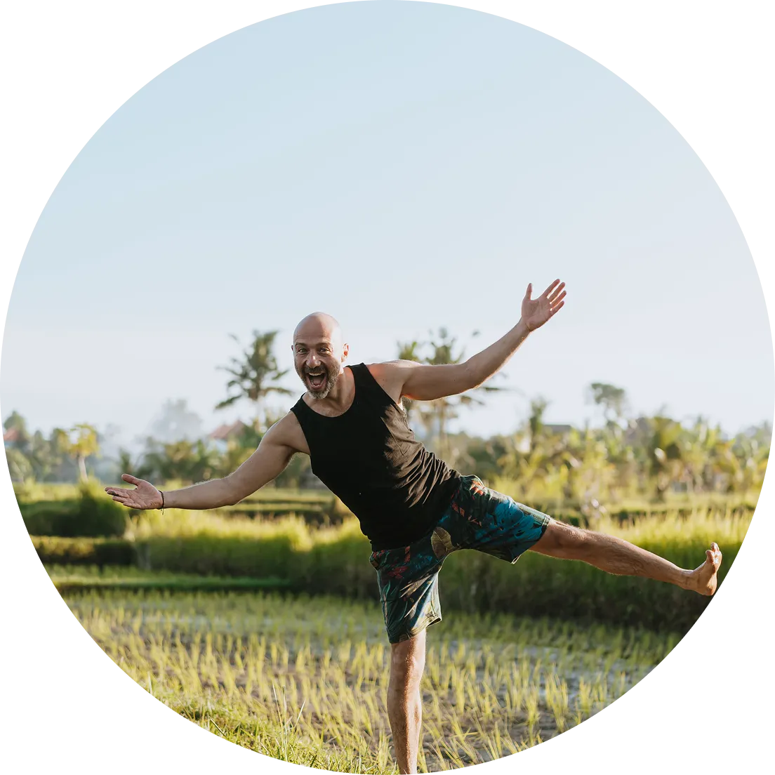 Alex Tsuk in Bali standing on one lag and his arms wide to welcome new students in his community of breathwork Teachers